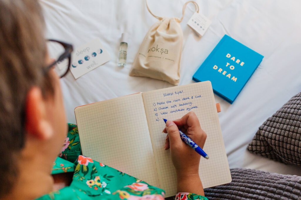 a woman in her forties sits on a hotel bed and writes in her journal