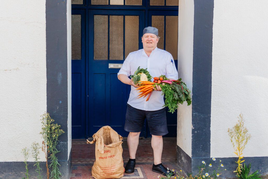 Eliot Seabourn-Wren, co-owner of the carlton Hotel in Ilfracombe stood in a doorway holding locally grown carrots