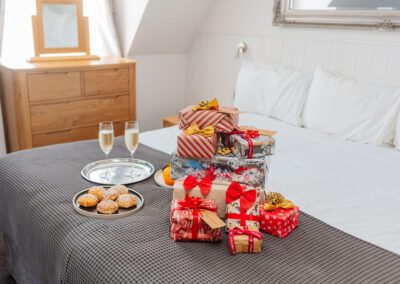 A hotel bed at The Carlton Hotel in Ilfracombe is stacked high with christmas gifts. A plate of mince pies and two glasses of champagne are on a tray on the bed