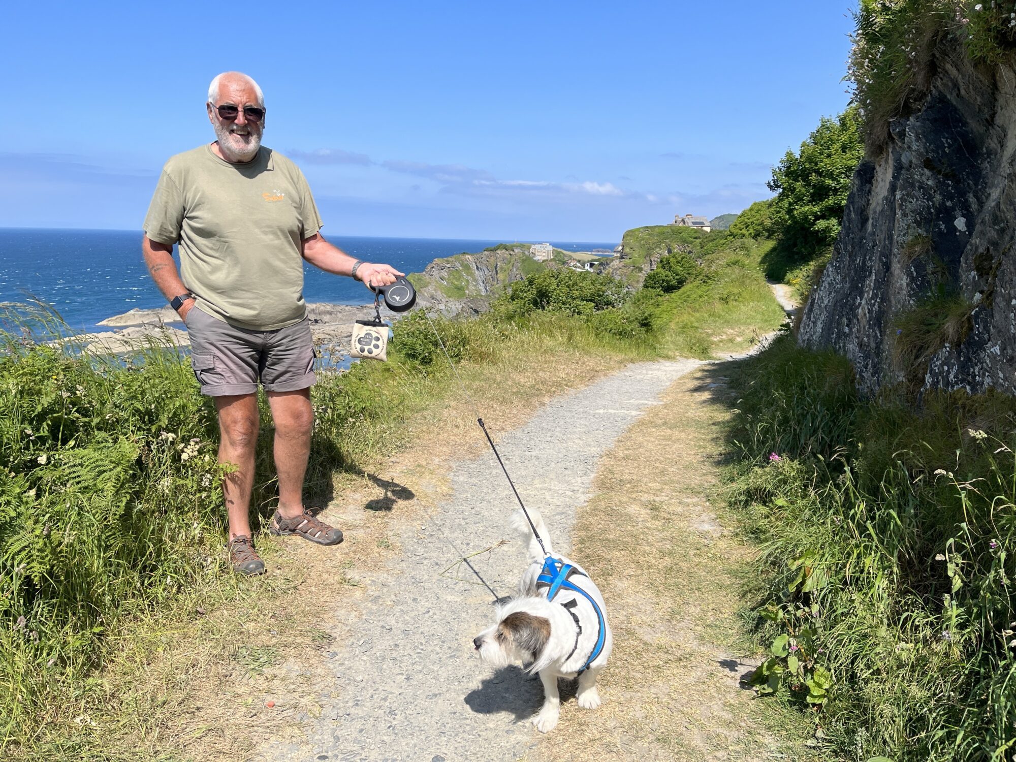 A man walking a small dog on the South West Coast Path in North Devon